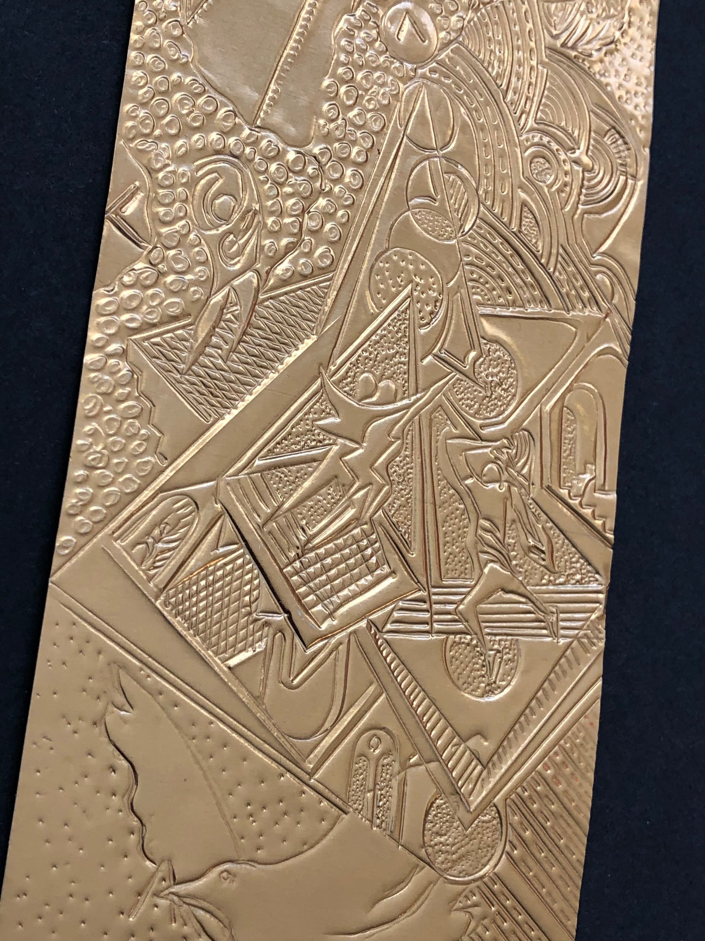Engraving on a bronze sheet with intricate geometric patterns, mounted on black card.