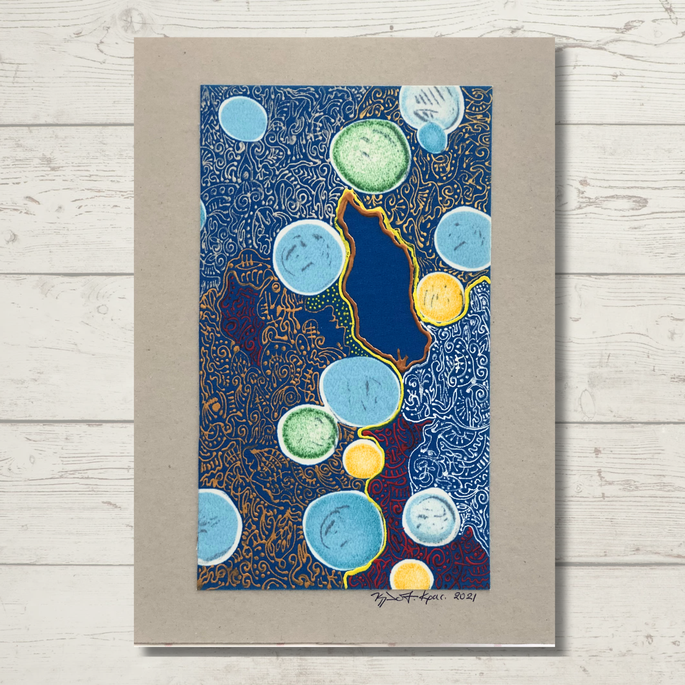 A drawing on cardboard featuring an abstract composition with various colored circles and dots, predominantly blue, with artist's signature at the bottom.