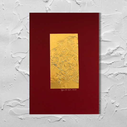 A gold-plated, engraved metal foil art piece mounted on a red backing, displayed against a textured white background.